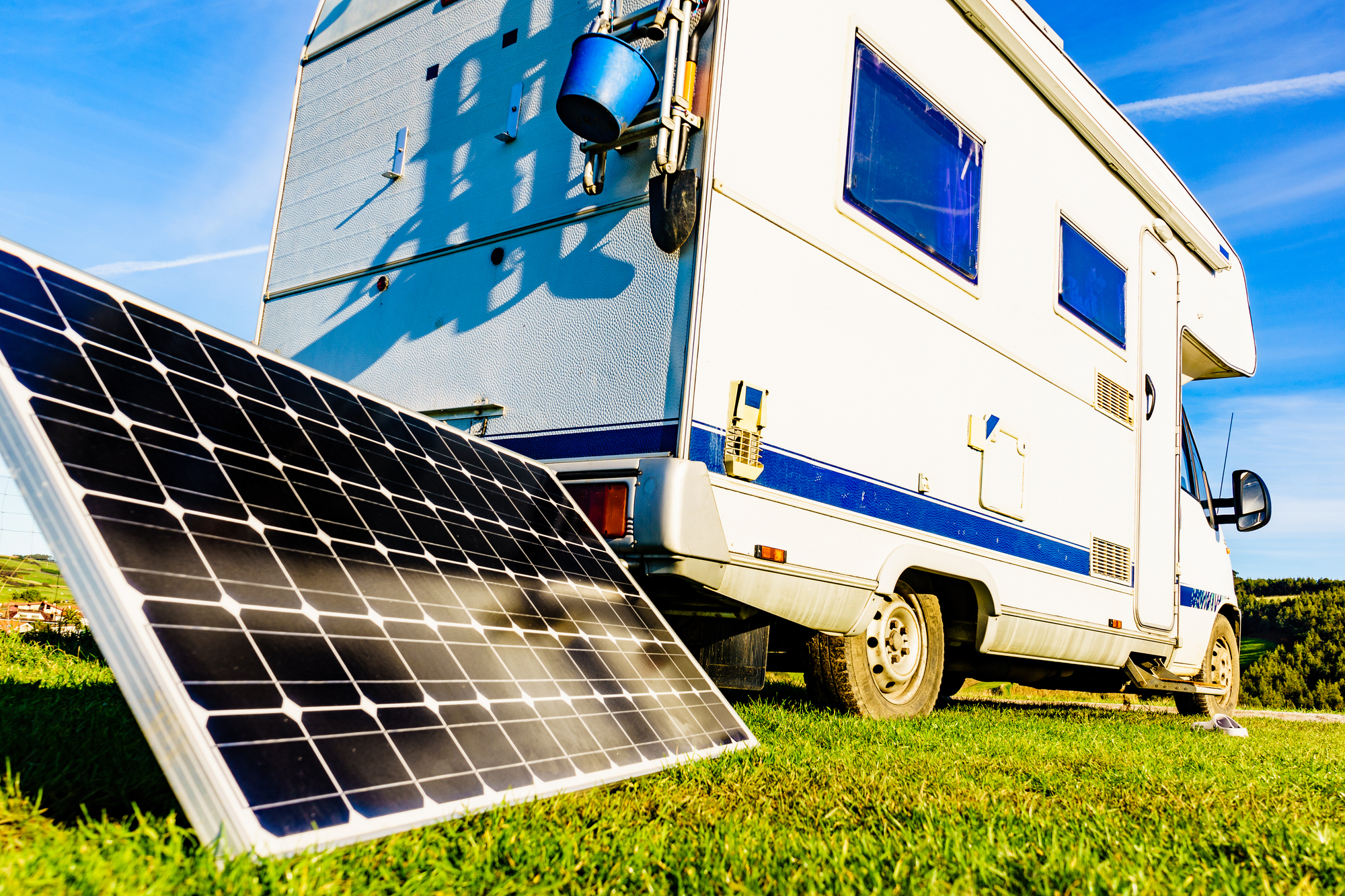 Charging battery at camper car. Caravan with portable solar photovoltaic panel camping on Verdicio beach, Asturias coast, northern Spain.